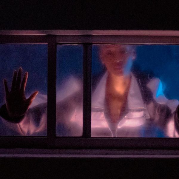 Person in a focused yoga pose, silhouette against a dark background with abstract mint-colored light patterns.